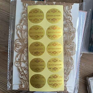 Close-up of gold foil invitation stickers with laser cut glitter envelopes for weddings