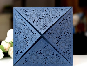 Macro detail of laser-cut glitter navy blue invitation card with intricate mandala floral patterns