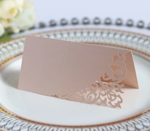 Detail of laser-cut wedding place card in pale pink on a decorative dinner plate