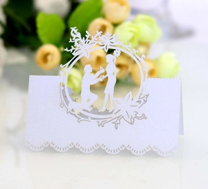 Detail of laser-cut white wedding place card featuring a romantic proposal design