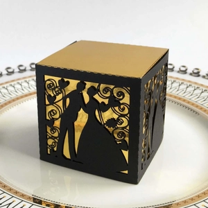 Macro view of laser-cut black and gold wedding favor box with silhouette on porcelain