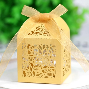 Close-up of golden hollow laser-cut gift box featuring intricate floral patterns and silk ribbon