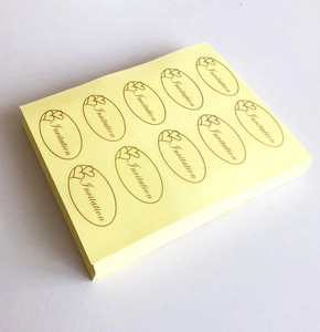 Close-up of gold oval Invitation envelope stickers with heart icons on backing paper