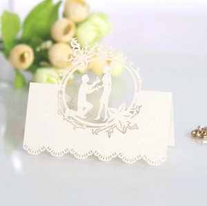 Laser cut white pearl paper place card featuring a romantic proposal silhouette design