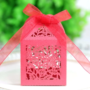 Detailed close-up of a red laser-cut wedding favor box with floral patterns and ribbon