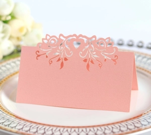 Detail view of pink laser-cut heart and rose place card on a decorative dinner plate