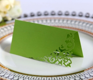 Detailed laser-cut scroll pattern on a dark green paper place card for wedding decor