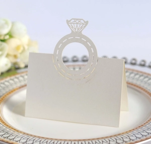 Elegant white laser-cut wedding place card with diamond ring design on dining plate