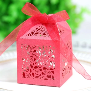 Detail of red laser-cut candy box with floral patterns and matching organza ribbon bow
