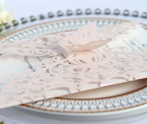 Detailed laser-cut pattern and 3D butterfly ornament on a pink wedding invitation card