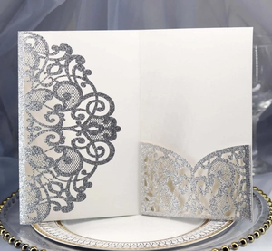 Detail of laser-cut silver glitter wedding invitation with elegant lace hollow pattern