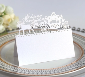 Detailed laser-cut white pumpkin carriage wedding seat card on an elegant porcelain plate