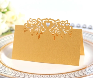 Close-up of golden laser-cut heart seat card with floral hollow pattern on dinner plate