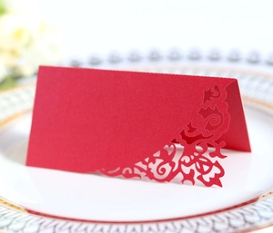 Detail of red laser-cut place card with elegant floral lace pattern on a white plate