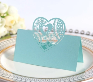 Detail of light blue laser-cut wedding place card with intricate hollow heart lace pattern