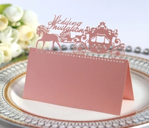 Macro detail of laser-cut royal carriage wedding place card in rose gold pearlescent paper
