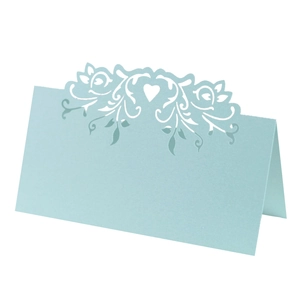 Close-up of laser-cut hollow heart and floral design on light blue wedding table card