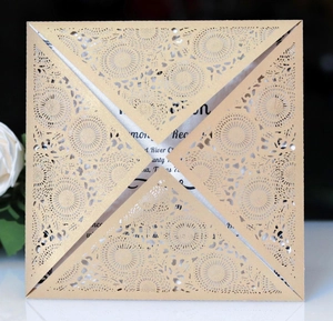 Detail showing the intricate laser-cut floral pattern on gold pearlescent invitation pocket