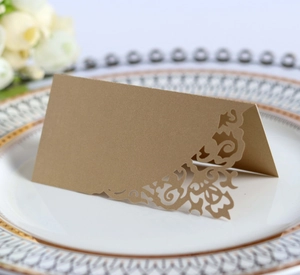 Detail view of a laser-cut gold wedding place card on a white decorative porcelain plate