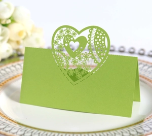 Detail of laser-cut heart seat card in green finish on a decorative white plate