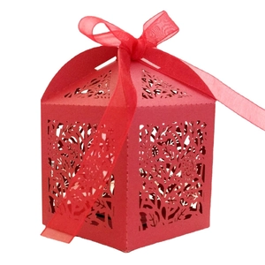 Red laser-cut wedding favor box with intricate hollow plant patterns and ribbon bow