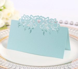 Detail of light blue laser-cut floral wedding place card with elegant heart pattern