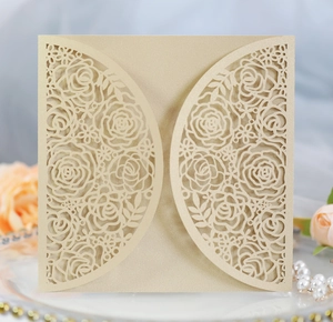 Macro shot of laser-cut rose hollow wedding invitation in champagne gold pearlescent paper