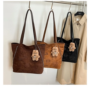 Trois sacs cabas en daim marron et noir avec pendentifs ours accrochés sur des cintres