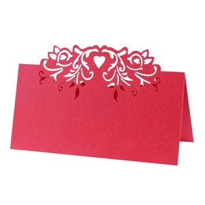 Macro view of a laser-cut red place card with elegant heart and floral patterns