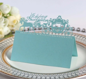 Detail of light blue laser-cut wedding place card with elegant royal carriage design