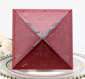 Detailed laser-cut floral pattern on a burgundy wedding invitation card with white inner sheet
