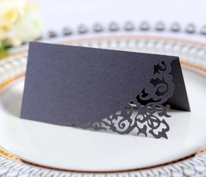 Detail of laser-cut lace pattern on black wedding place card placed on a dining plate