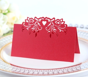 Macro detail of laser-cut red paper place card with floral and heart patterns for weddings