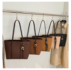 Detail view of five large faux leather tote bags with tassels in various autumn colors