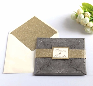 Détail d'invitation découpée au laser avec bande dorée scintillante et enveloppe assortie