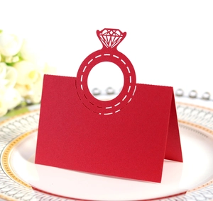 Detail of red laser-cut diamond ring place card on white porcelain plate with pearls