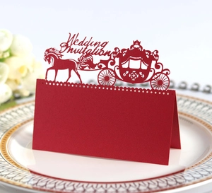 Macro detail of laser-cut red royal carriage wedding invitation card on a gold plate