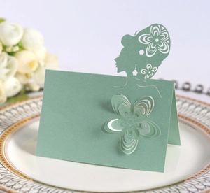 Detail of laser-cut sage green wedding place card with elegant female profile on white plate