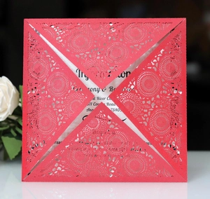 Detail of red laser-cut invitation cover with intricate hollow pattern and white inner card
