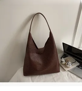Detailed view of dark brown woven oversized hobo bag on a minimalist office desk