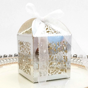Macro detail of laser-cut floral pattern on silver wedding favor box with white ribbon