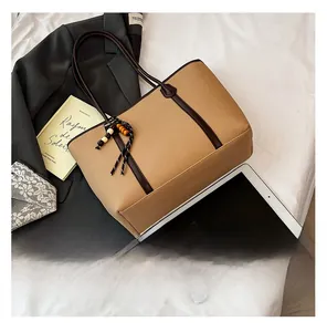 Flat lay of khaki tote bag with dark brown straps and wooden bead accessory