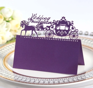 Macro shot of dark purple laser-cut wedding seat card with elegant carriage design