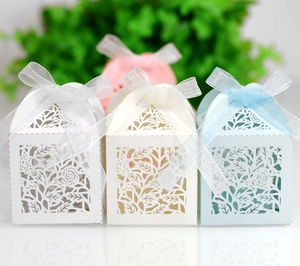 Close-up of laser-cut floral wedding favor boxes with elegant organza ribbon bows
