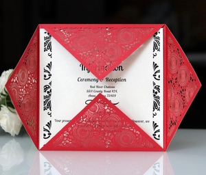 Close-up of red laser-cut floral wedding invitation with white inner card and rose decor