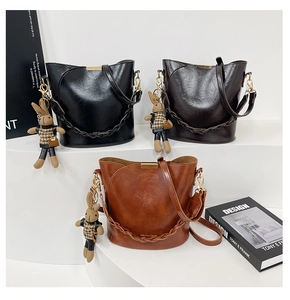 Close-up of three faux leather bucket bags in black, dark coffee and brown with charms