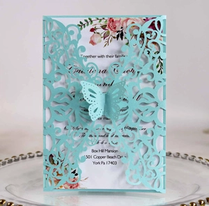 Detail of laser-cut wedding invitation in light blue with delicate butterfly and floral design