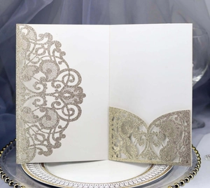Detailed laser-cut champagne gold glitter wedding invitation with intricate floral lace pattern