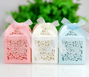 Detailed laser-cut hollow rose patterns on pink, cream, and blue paper wedding favor boxes