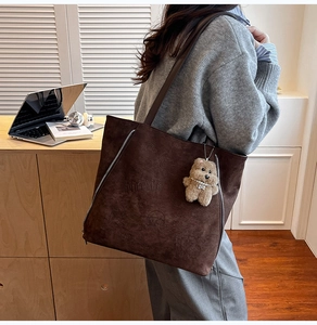 Détail du grand sac cabas en daim marron foncé avec imprimé Ninaite et charm ours peluche